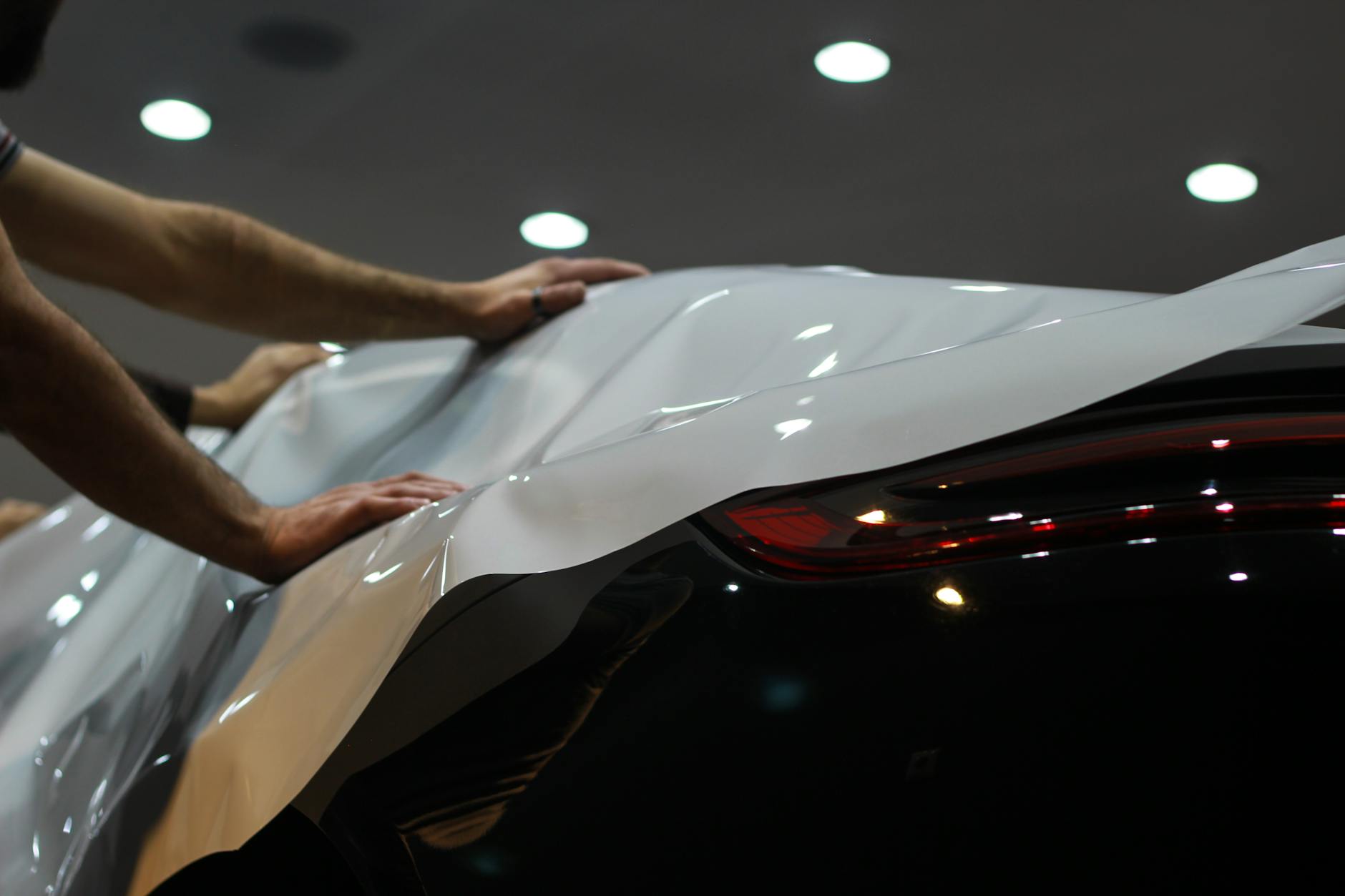 men putting white cover on modern car
